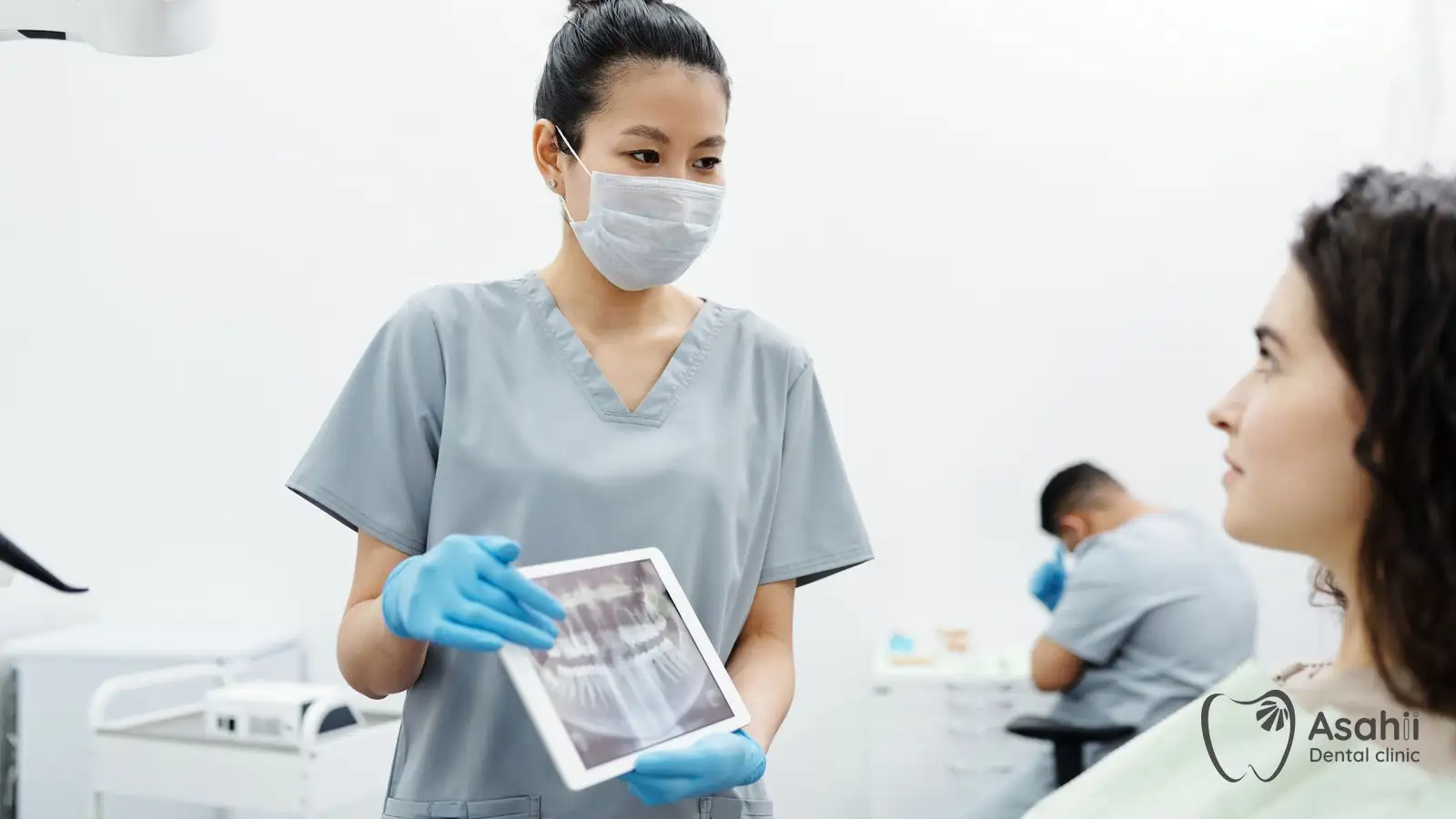 The dentist shows the patient an X-ray while explaining the implant procedure